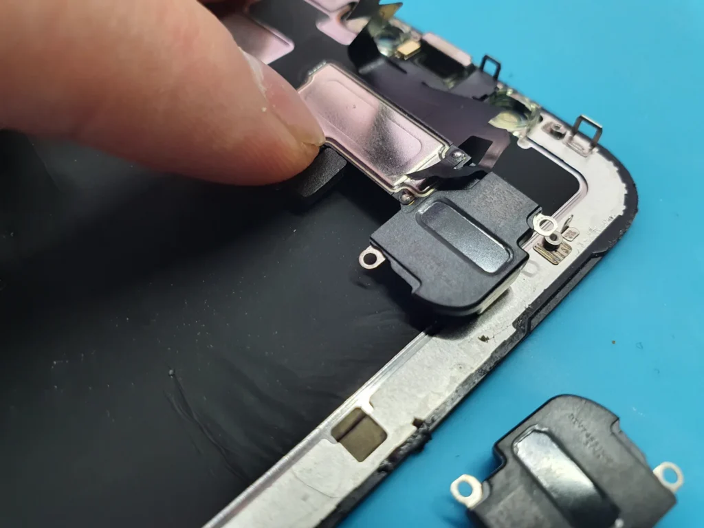 Динамик и разобранный iPhone во время ремонта